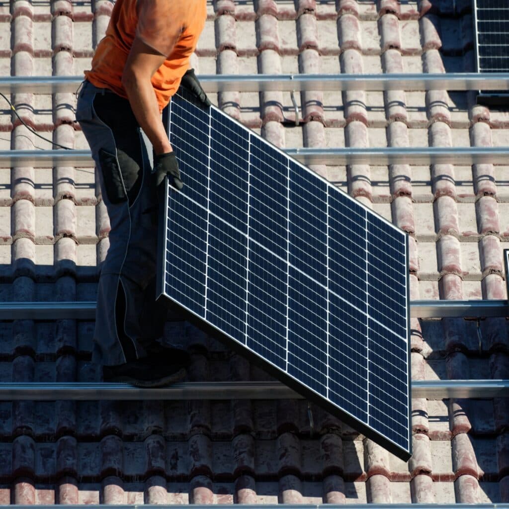 Mitarbeiter steht auf einem Dach in Bochum und hält ein Solarpanel